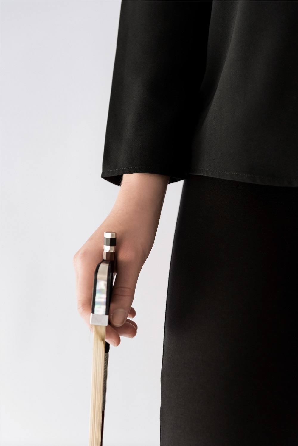 hand holding cello bow with long sleeve