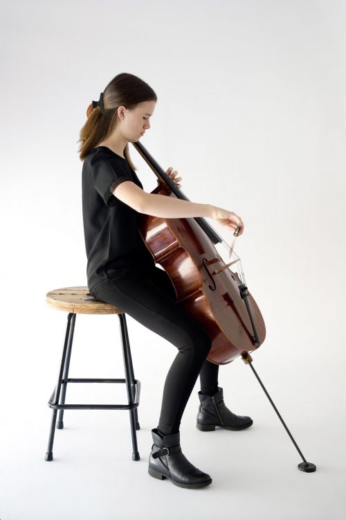 girl sitting playing cello in concert blacks