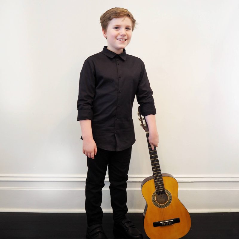 boy posing with guitar wearing black buttoned shirt
