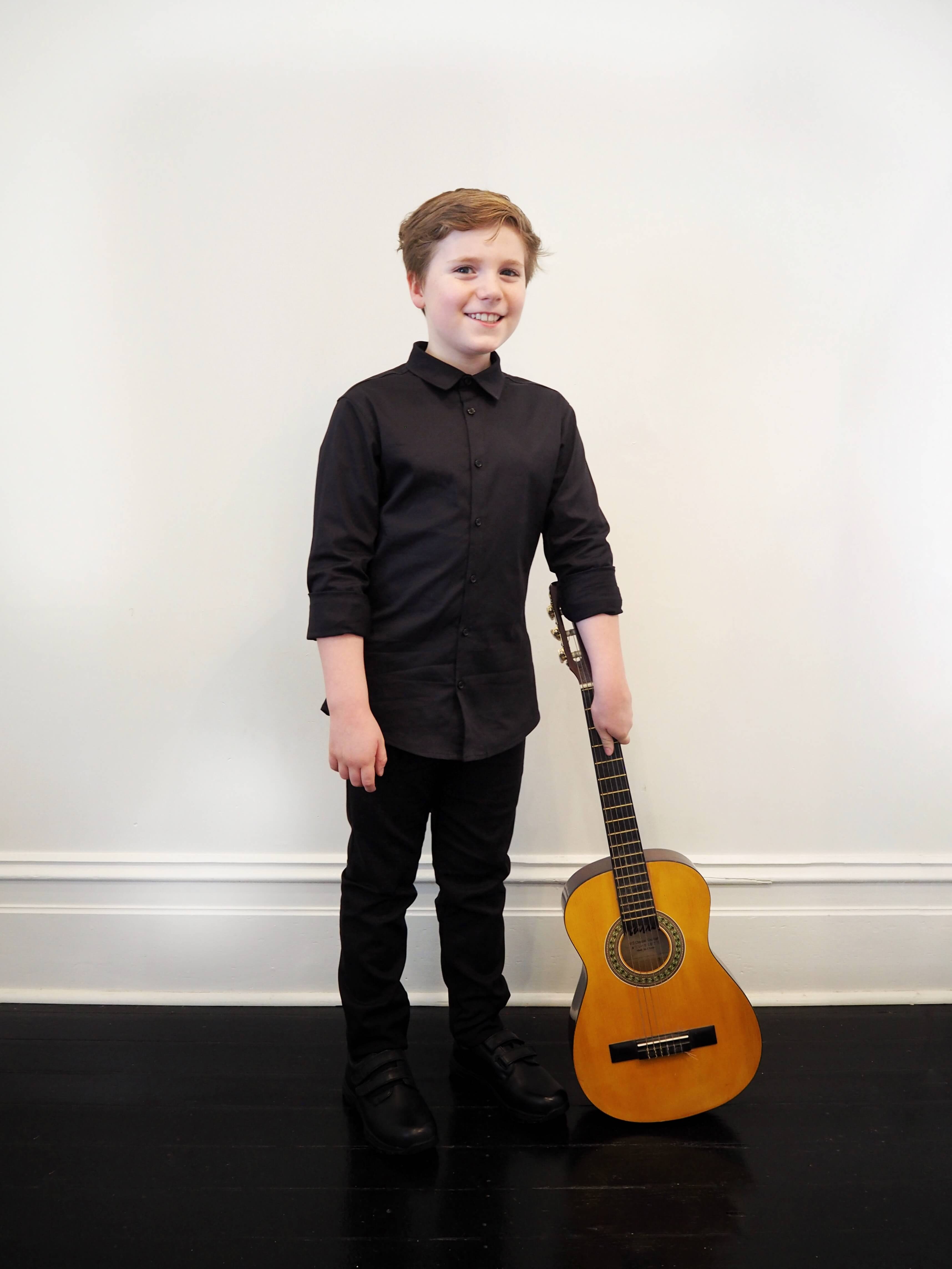 boy posing with guitar wearing black buttoned shirt